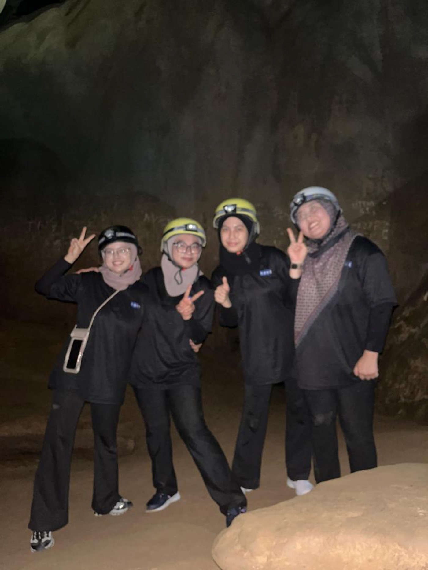 Team members posing inside Gua Tempurung cave with helmets and headlamps during corporate team building