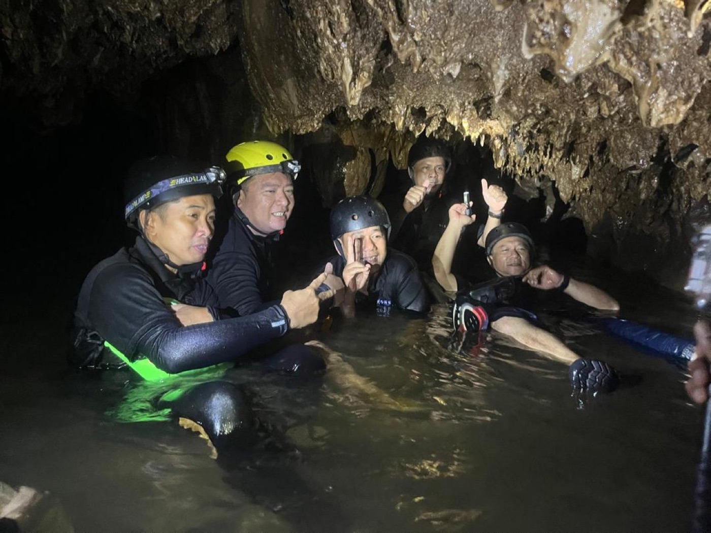Corporate team navigating underground river inside Gua Tempurung cave during team building program