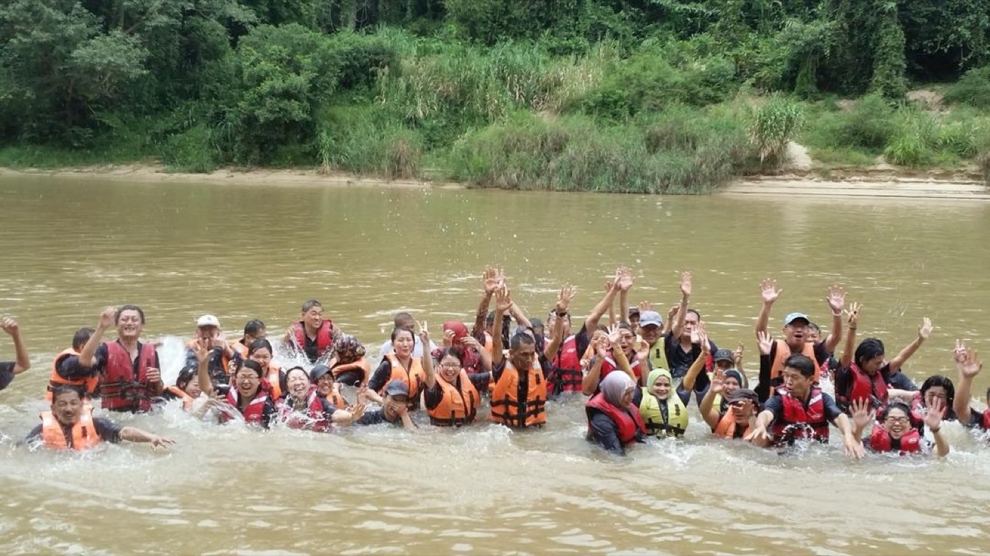 Large corporate group celebrating in Sungai Kampar river after completing team building rafting program in Gopeng